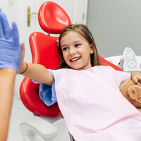 smiling child giving dentist high-five in treatment chair