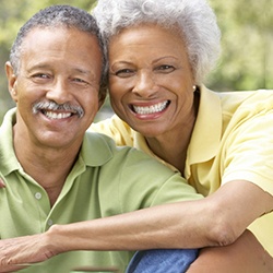 Older couple smiling while wearing dentures