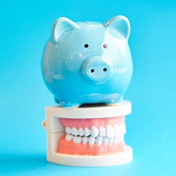 Blue piggybank sitting on top of full dentures