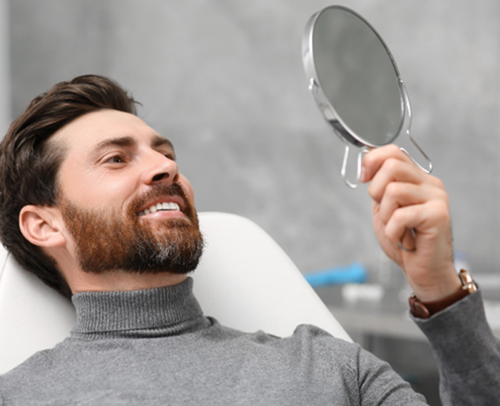 Midwest City patient hiding smiling at teeth in mirror after dental bonding