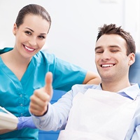 Smiling man in dental chair giving thumbs up
