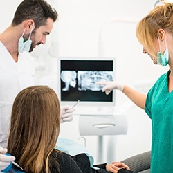 Dentist and patient pointing at digital dental x-ray on computer monitor
