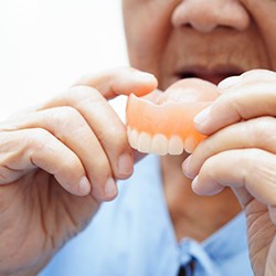 a person holding a set of custom dentures