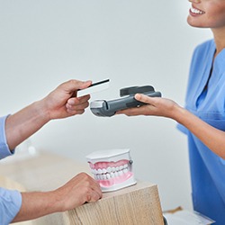 Patient handing over card to pay for dental care