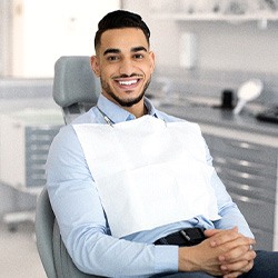 Male dental patient sitting in dental chair with hands folded