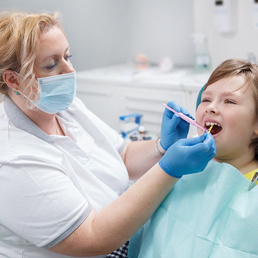 A dentist applying fluoride to a child’s teeth