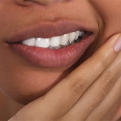 Woman rubbing jaw while recovering from dental implants in Midwest City, OK