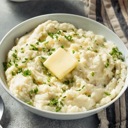 Bowl of mashed potatoes with butter next to tablecloth