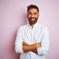 a smiling person against a pink backdrop