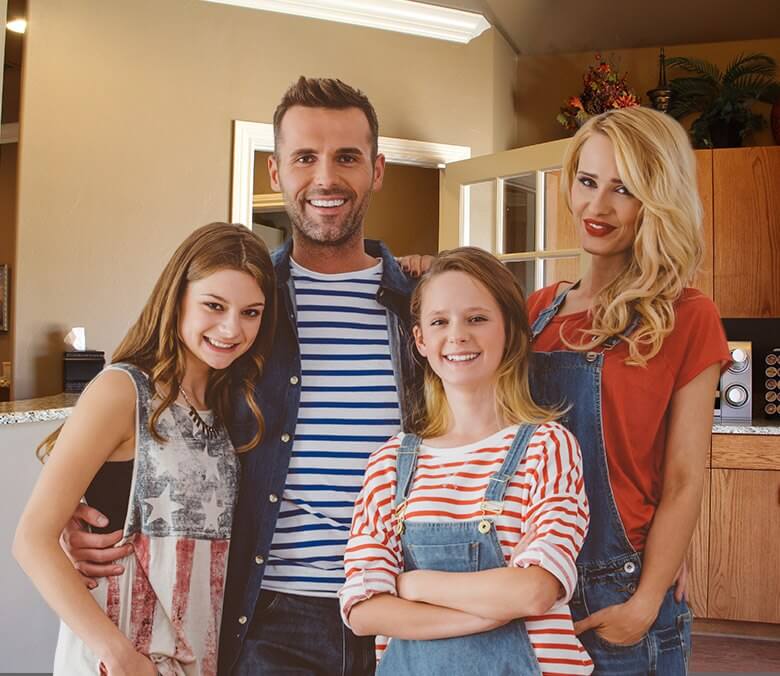 A family of four smiling big indoors