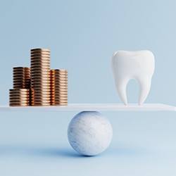 a tooth and coins balancing on a scale