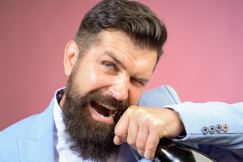 Man opening Champagne bottle with teeth