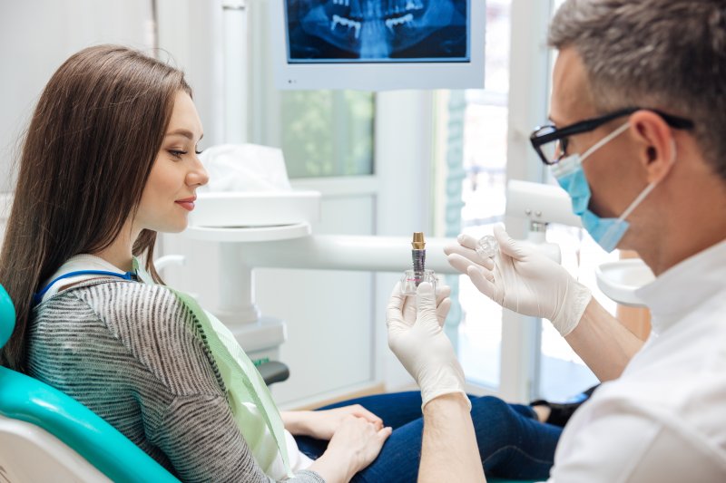 Dentist showing patient a dental implant during a consultation