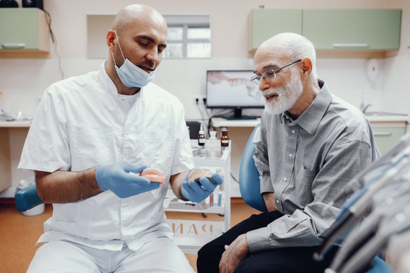 Dentist showing a patient how to use denture adhesive