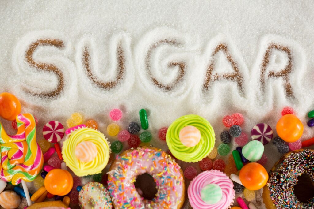 Word "Sugar" written in spilled sugar next to a pile of sweets