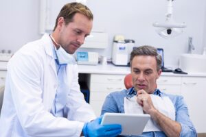 Dentist showing patient tablet as they discuss questions.